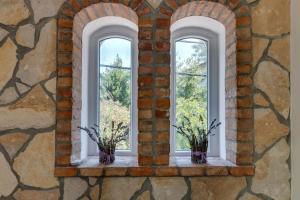 three windows in a brick wall with flowers in vases at Laguna in Nerezine