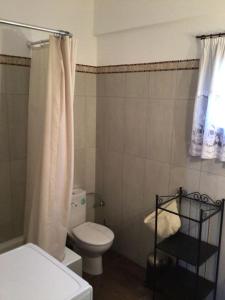 a bathroom with a toilet and a shower curtain at An all comforts home in Koroni