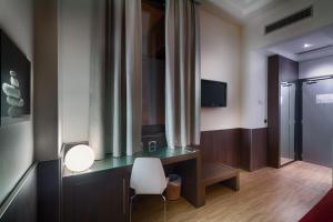 ローマにあるホテル ラガネリのデスク、椅子、テレビが備わる客室です。