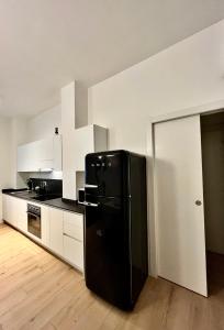 a black refrigerator in a kitchen with white cabinets at Corso Lodi Apartment in Milan