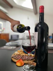 una persona che versa una bottiglia di vino in un bicchiere di vino di Antica Dimora a Levico Terme
