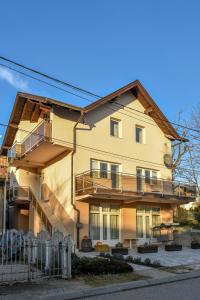une maison jaune avec un balcon et une clôture dans l'établissement Apartment Studenac, à Banja Luka