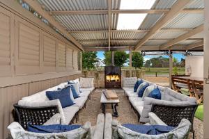 a covered patio with couches and a fireplace at Fentons Run High Range in Joadja Creek