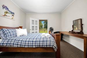 een slaapkamer met een bed en een bureau met een televisie bij Fentons Run High Range in Joadja Creek