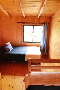 a bedroom with a bed and a window in a cabin at Cabanas L'ESCALE in Coñaripe
