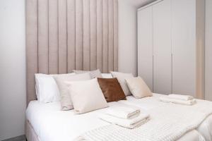 een groot wit bed met witte kussens bij Lovely 1 bedroom apt w/pool. Haneviim st jerusalem in Jeruzalem