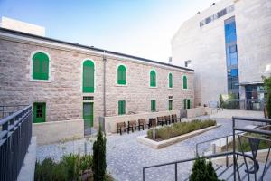 een gebouw met groene ramen en banken op een binnenplaats bij Lovely 1 bedroom apt w/pool. Haneviim st jerusalem in Jeruzalem