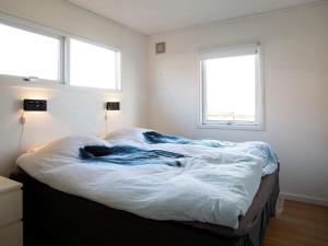 ロッケンにあるThree-Bedroom Holiday home in Løkken 63の大きなベッド1台(窓2つ付)が備わるベッドルームです。