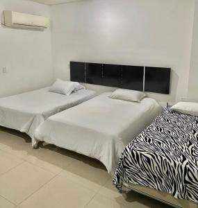dos camas sentadas una al lado de la otra en una habitación en Hotel Barrancabermeja Plaza, en Barrancabermeja
