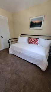 a bedroom with a bed with white sheets and red pillows at Camp Kingsbury- SEAWORLD and MEDICAL Center Best LOCATION in San Antonio