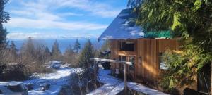 a cabin in the snow with a view of the water at Ocean Views & Sunset Beach Cabin with soaker tub & fire pit in Powell River