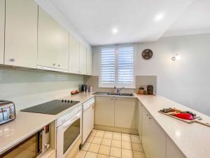 a kitchen with white cabinets and a sink at Villa Andante in Pokolbin
