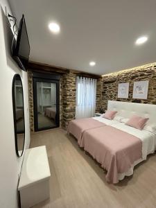 - une chambre avec un grand lit et une télévision dans l'établissement A CASIÑA DE ISABEL, à Arzúa