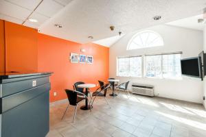 Zimmer mit orangefarbenen Wänden sowie einem Tisch und Stühlen in der Unterkunft Motel 6-Olathe, KS in Olathe