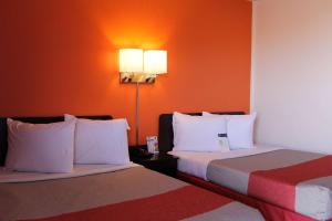 2 camas en una habitación de hotel con paredes de color naranja en Motel 6-Goodland, KS, en Goodland