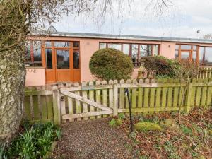 a house with a wooden fence and a house at Woodpecker in Ivegill