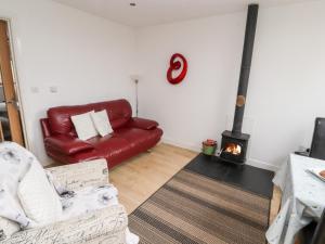 ein Wohnzimmer mit einem roten Ledersofa und einem Kamin in der Unterkunft Nuthatch in Ivegill