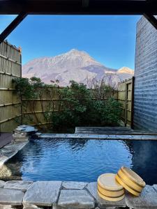 una piscina con due sgabelli di fronte a una montagna di 湯布院 旅館 やまなみ Ryokan YAMANAMI a Yufu