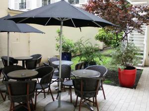 un grupo de mesas y sillas bajo una sombrilla en New Hotel Saint Lazare, en París