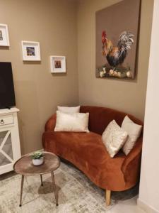uma sala de estar com um sofá castanho e uma galinha na parede em Best Western Grand Hotel de Bordeaux em Aurillac