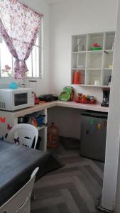 eine Küche mit einer Theke mit einer Mikrowelle und einem Fenster in der Unterkunft Alojamiento Colors in Mexiko-Stadt