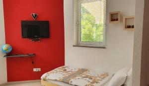 a room with a red wall with a flat screen tv at Ferienwohnung-Ginkgo-A3 in Banjole