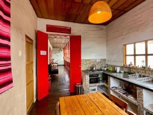 een keuken met rode muren en een houten tafel bij Hostal Tralala Salento in Salento