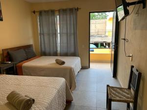 Habitación con 2 camas, silla y ventana en HOTELITO SAN IGNACIO en San Ignacio
