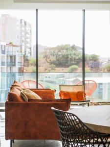 a couch and chairs in front of a large window at Filomena Apartments BOHÈME in Mindelo