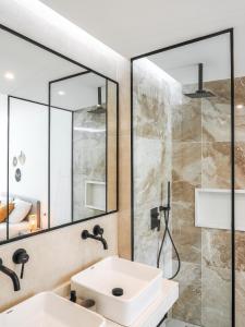 a bathroom with a sink and a shower with a mirror at Filomena Apartments BOHÈME in Mindelo