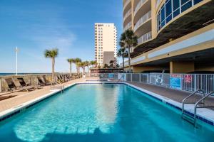 a swimming pool with chairs and the ocean in the background at Ocean Villa 1706 in Panama City Beach