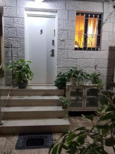 a white front door of a house with potted plants at Lovely 2 bedroom unit, Shivtey Israel, Jerusalem in Jerusalem