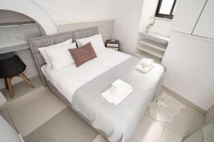 una piccola camera da letto con un letto con lenzuola e cuscini bianchi di Lovely 2 bedroom unit, Shivtey Israel, Jerusalem a Gerusalemme