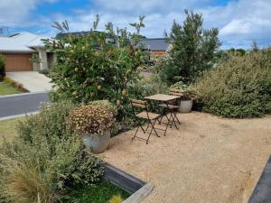 une table et des chaises dans un jardin avec des plantes dans l'établissement ADAGIO, à Point Lonsdale