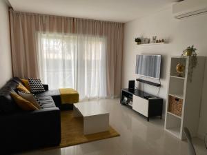 a living room with a couch and a tv at Garden Hill Apartment in Albufeira