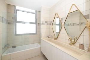 y baño con bañera, lavabo y espejo. en Amazing 3 bedroom, Shalem Tower, en Jerusalén