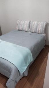 un letto con lenzuola e cuscini blu su un pavimento in legno di Nosso cantinho a Poços de Caldas