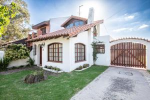 a white house with a gate and a yard at Chalet en Barrio Parque in Mar del Plata