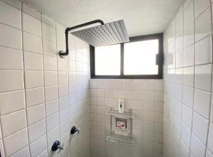 a white tiled shower with a window in a bathroom at Lovely Depa. Forosol Palacio Airport 10 Min in Mexico City
