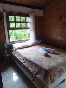 Cama en habitación con ventana en Sítio Recanto Amado., en Santa Teresa