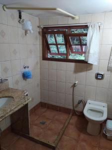 a bathroom with a toilet and a sink and a window at Sítio Recanto Amado. in Santa Teresa