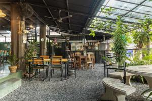 un restaurante con mesas, sillas y plantas en Blockhouse Hostel, en Ban Na We