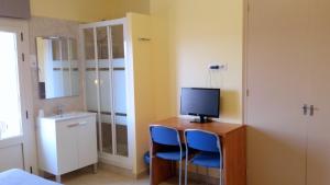 a room with a desk with two blue chairs and a television at Hostal Capitol Ramblas in Barcelona