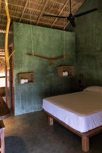 a bedroom with a bed and a green wall at COCOS HOTEL in Zipolite