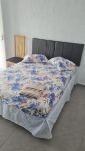 a bed with a floral comforter on top of it at Pousada Félix in Curitiba