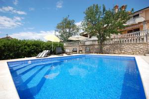 een groot zwembad met blauw water voor een gebouw bij Family friendly apartments with a swimming pool , Krk - 20500 in Malinska