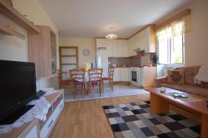 een woonkamer met een bank en een tafel en een keuken bij Family friendly apartments with a swimming pool , Krk - 20500 in Malinska