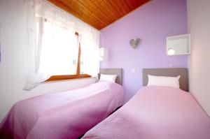 2 Betten in einem Zimmer mit lila Wänden und einem Fenster in der Unterkunft Apartments with parking space Vantacici, Krk - 20507 in Malinska