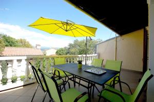 ein Tisch und Stühle auf einem Balkon mit einem gelben Sonnenschirm in der Unterkunft Apartments with parking space Vantacici, Krk - 20507 in Malinska + 7 Fotos