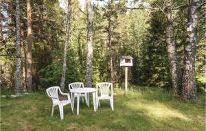three chairs and a table in a yard with a bird feeder at 2 Bedroom Nice Home In Årjäng in Årjäng